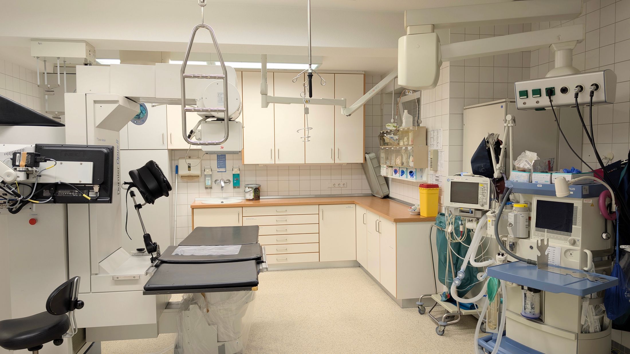 Sala de rayos X hospitalaria con tubo en suspensión de techo, mesa y bucky de pared