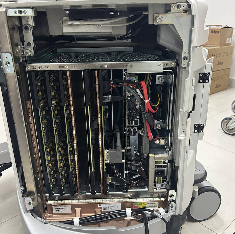 Chasis posterior abierto de un equipo de ultrasonido con tarjetas, cableado y módulos internos visibles