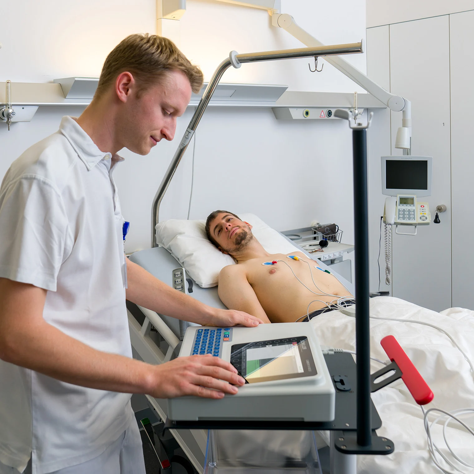 Profesional utilizando el SCHILLER CARDIOVIT AT-102 G2 junto a una cama hospitalaria
