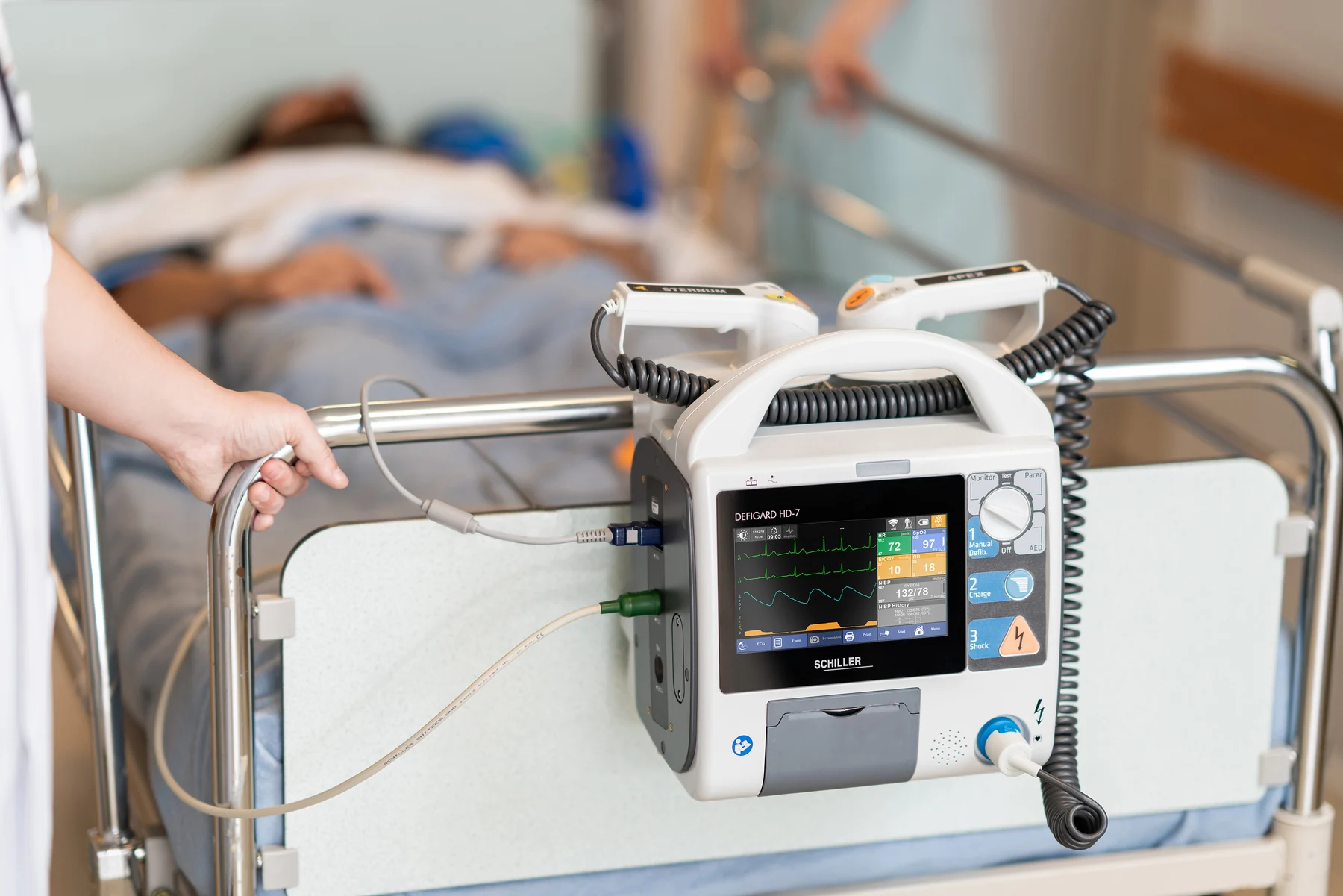 Monitor desfibrilador SCHILLER DEFIGARD HD-7 montado en la barandilla de una cama hospitalaria