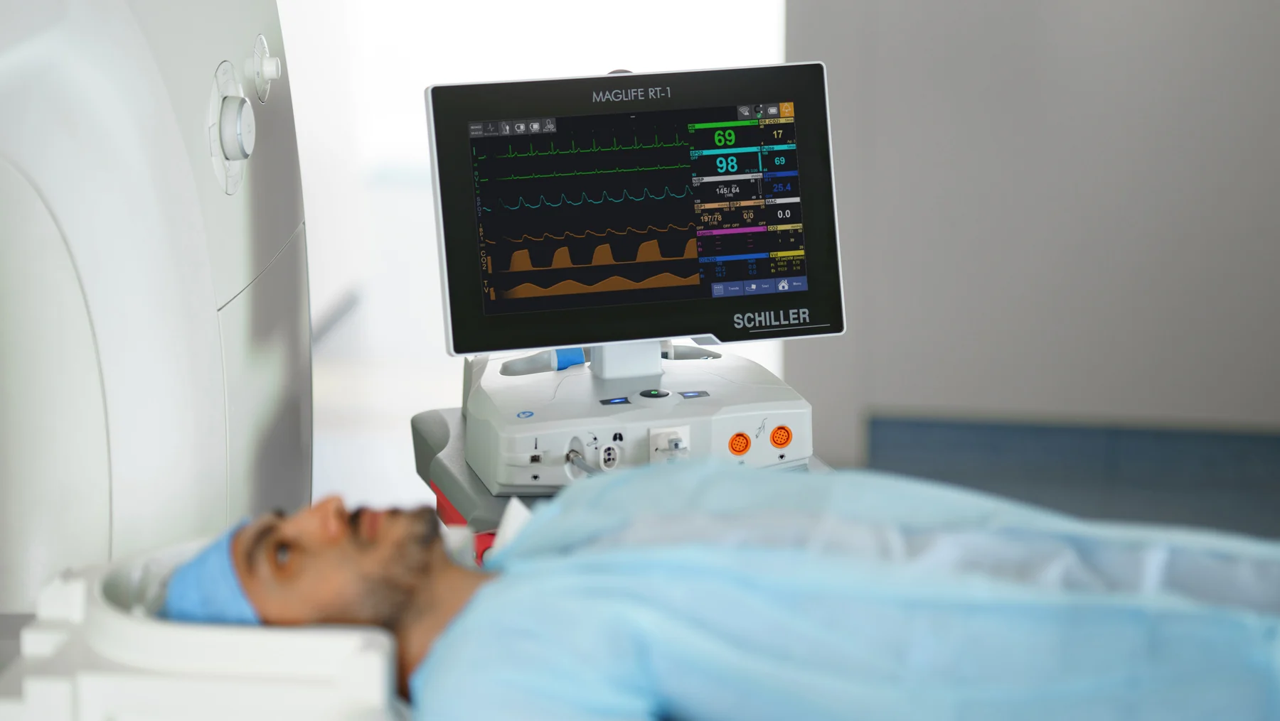 Monitor SCHILLER MAGLIFE RT-1 junto a un paciente recostado cerca del equipo de resonancia magnética