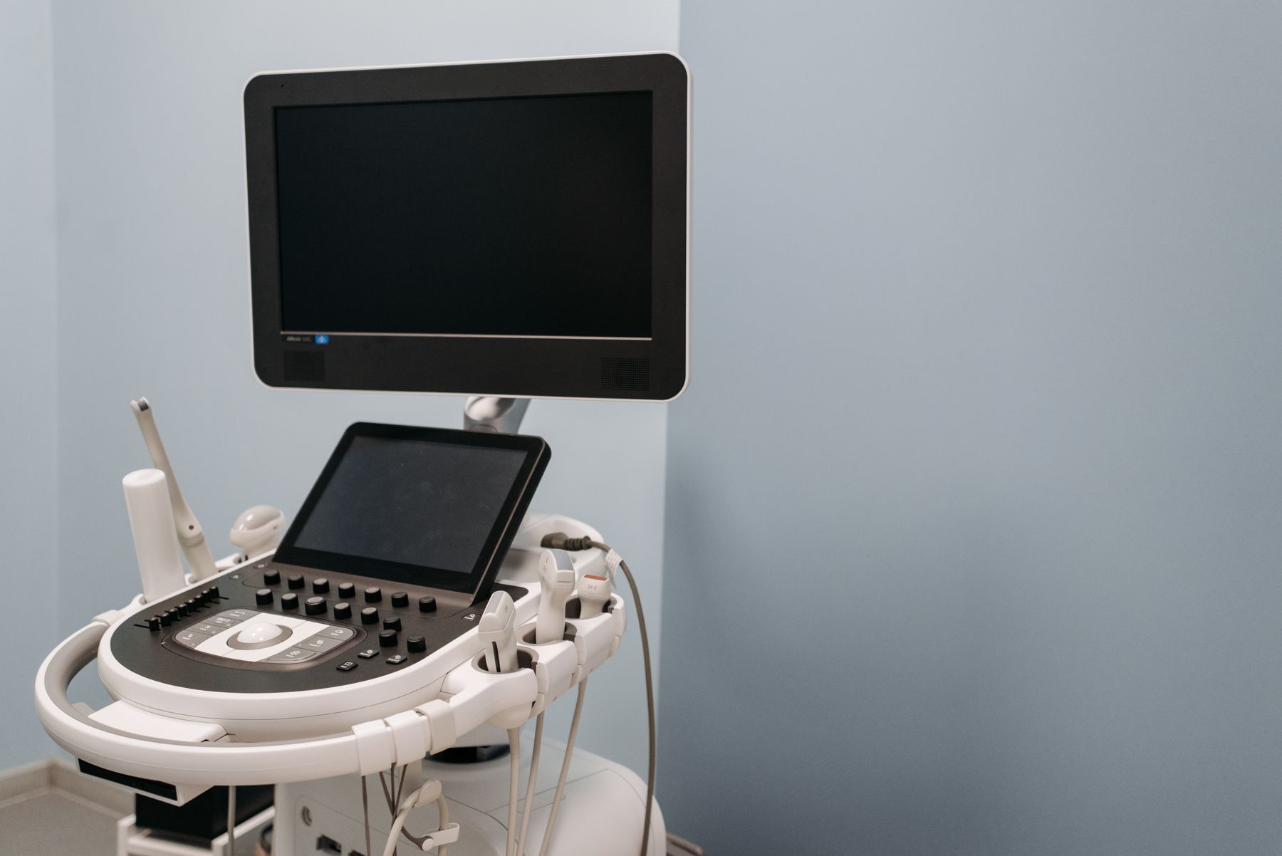 Equipo de ultrasonido con monitor, panel de control táctil y transductores en su soporte