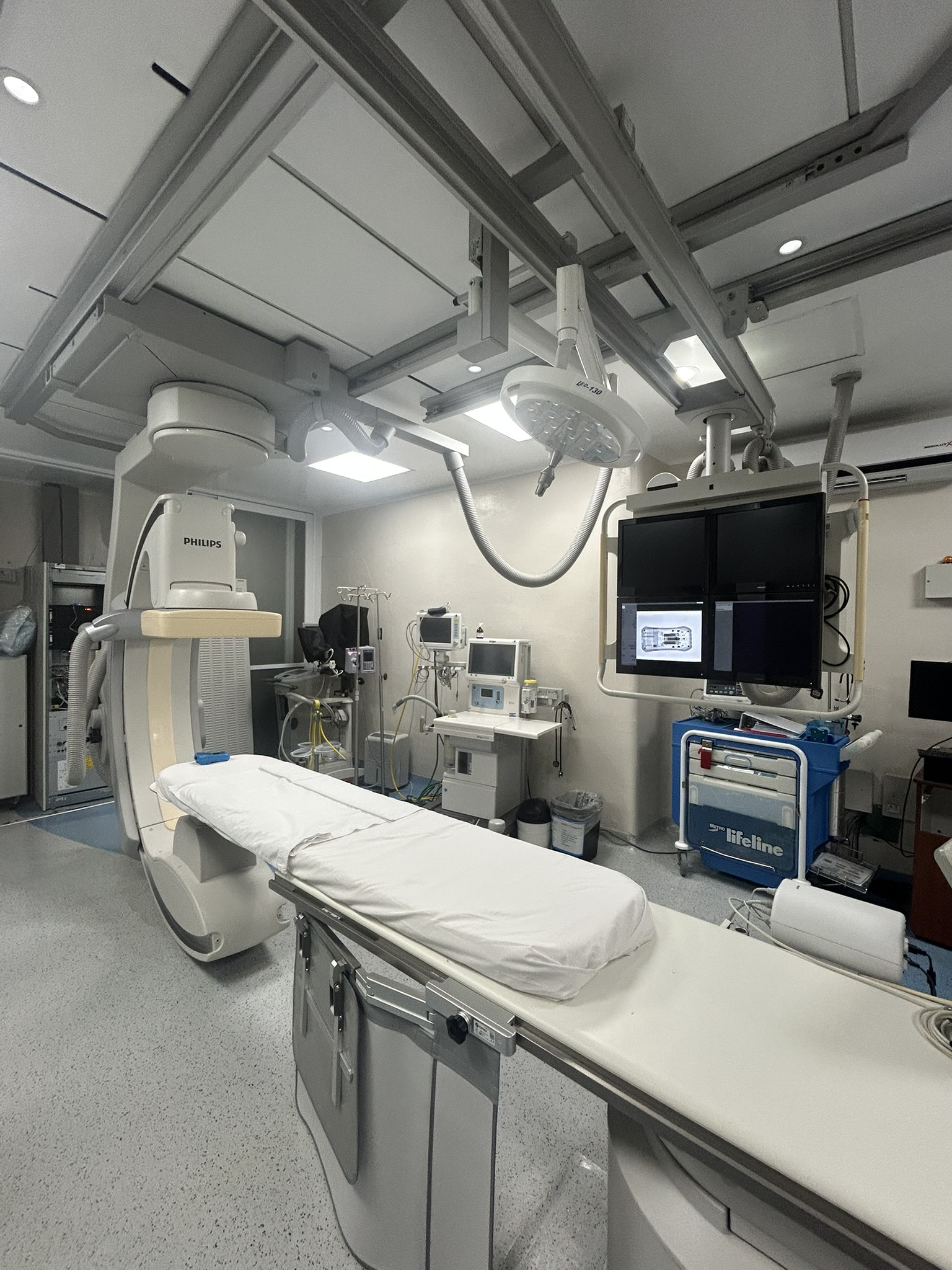 Sala de hemodinamia con angiógrafo Philips, mesa de exploración y monitores suspendidos